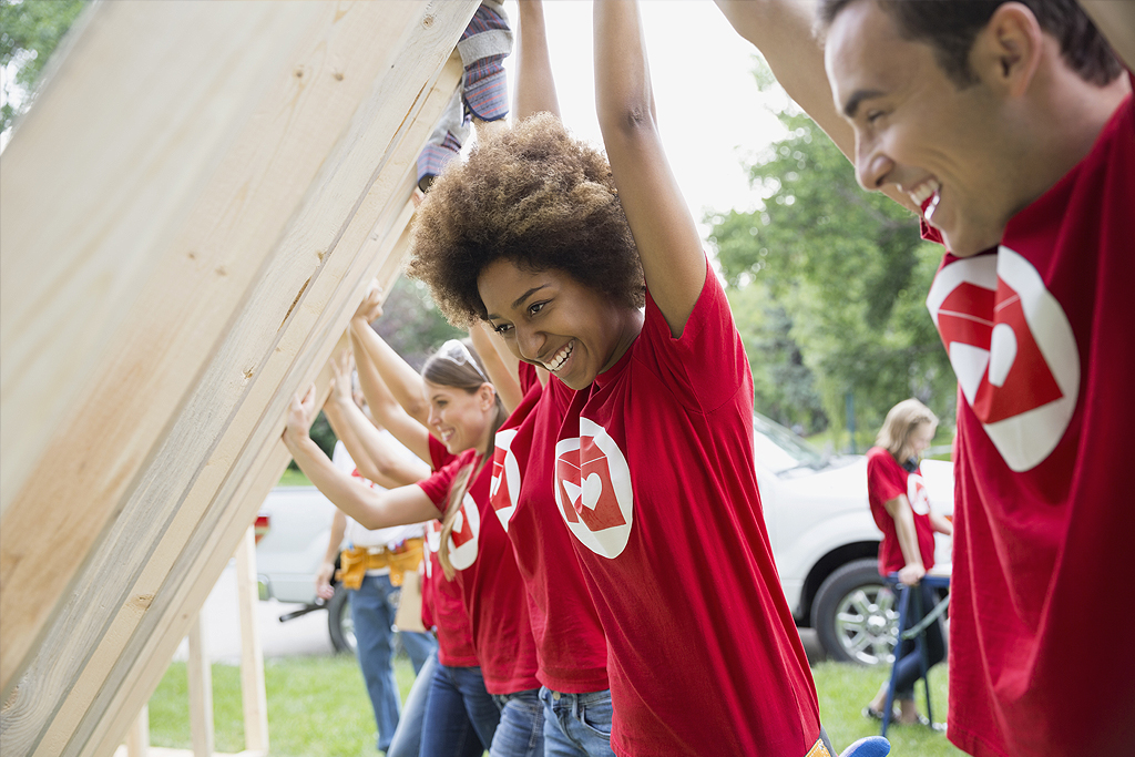 Smiling volunteers lifting construction frame